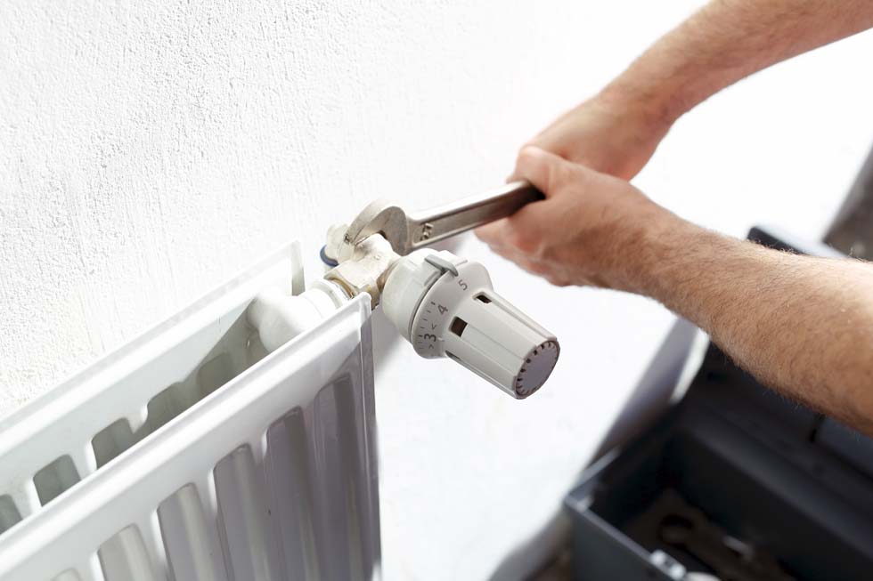 Plombier en train de vérifier le serrage d'un radiateur