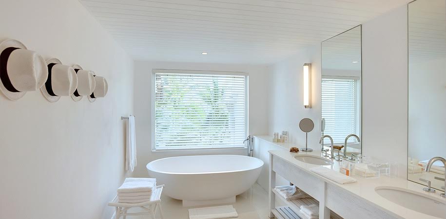 Salle de bain moderne avec mur blanc et baignoire devant une grande fenêtre