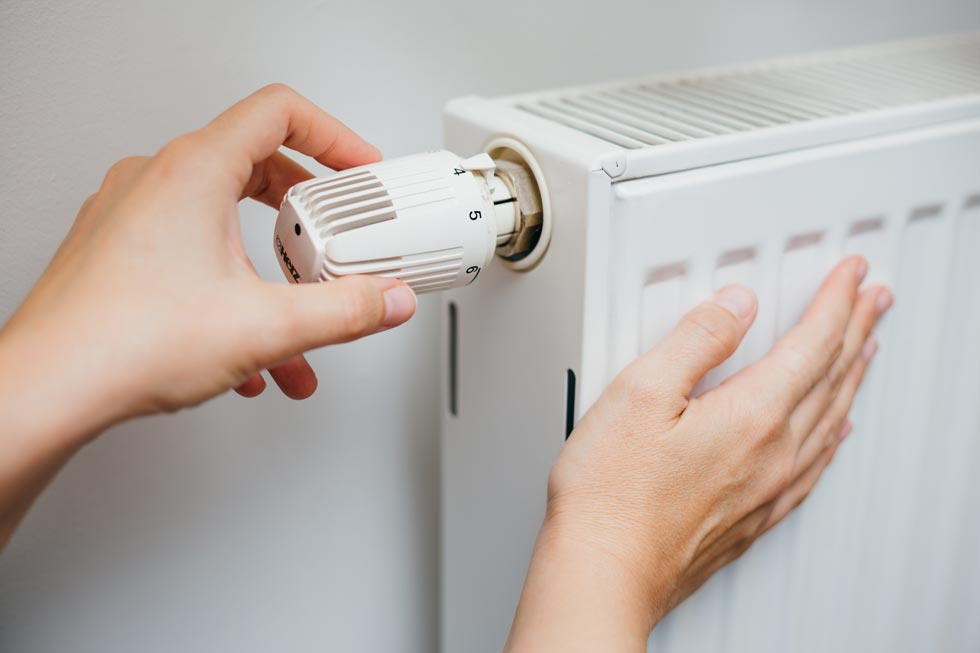 Main féminine réglant la température du radiateur sur le thermostat